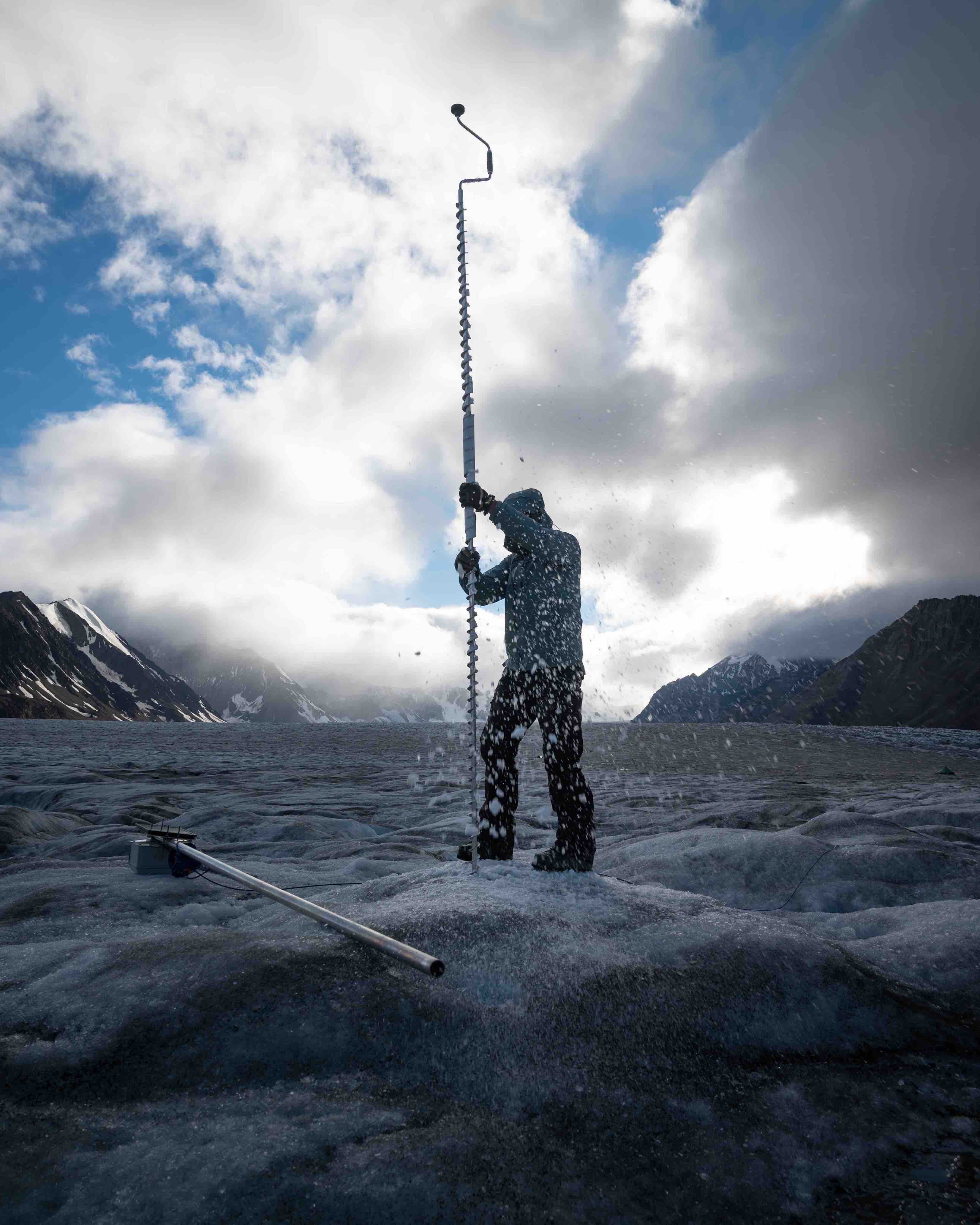 Menschen in der Forschung 3. Preis: The hard work of drilling into glacier ice. Camilo Rada taking out the tall ice auger from Kaskawulsh Glacier in the Yukon while drilling a five meter hole to secure a data logger (pole on the left of the image). The station needs to measure the water pressure from a sensor hundreds of meters deep in a nearby moulin for the summer. Securing something on a melting glacier is no simple task. This was part of a network of similar stations to better understand how water moves through a glacier. By Giulio Saibene.