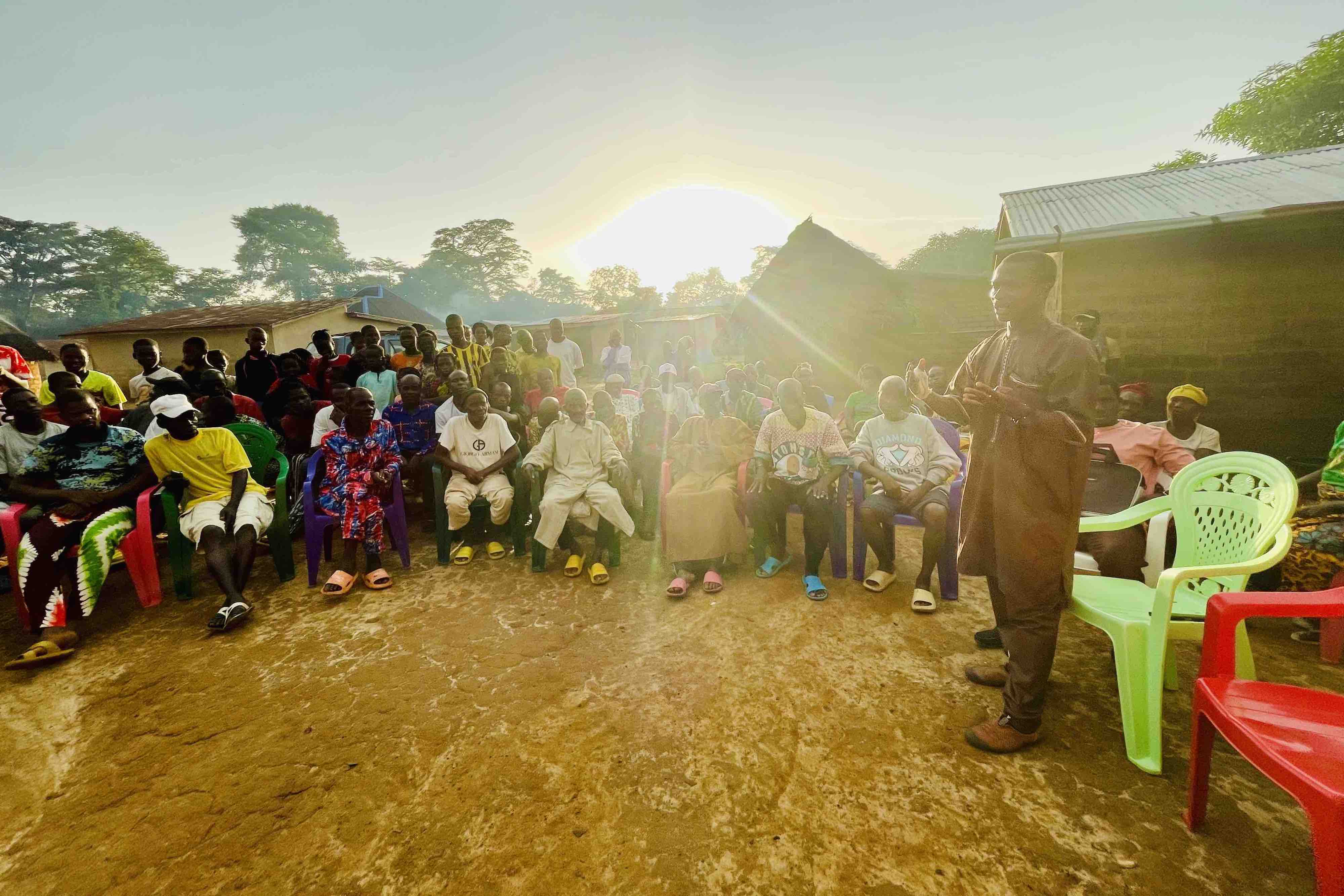 Interaktionen 3. Preis: Working together. Henry Didier Camara, the Guinean research team lead of the Nimba Chimpanzee Project, exchanges with the local community in Seringbara about chimpanzee research and conservation. Chimpanzees in the Nimba Mountains (Guinea), and elsewhere in Africa, are endangered due to habitat encroachment, extractive industries, and illegal human activities. The Nimba Chimpanzee Project takes a holistic approach to conservation based on scientific research, capacity building, and community engagement. Protecting wild chimpanzees and their habitat requires close and sustained collaboration with the local communities. By Kat Koops